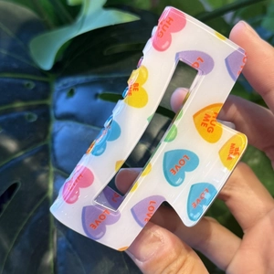 Square hair claw clip with colorful heart patterns and romantic text on white acrylic