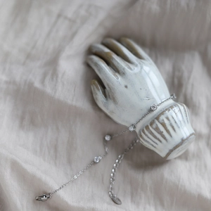 Macro detail of silver stainless steel chain bracelet with five sparkling white zircons