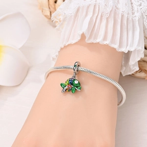 Close-up of a colorful enamel chameleon charm on a silver snake bone bracelet on a wrist