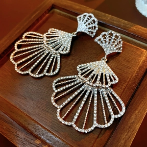Close-up of silver fan-shaped earrings with sparkling cubic zirconia on wood background
