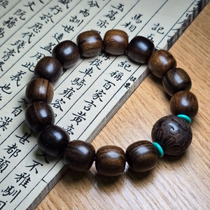 Gros plan de perles en bois d'agar avec breloque sculptée et intercalaires en turquoise