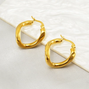 Elegant gold twisted oval hoop earrings in stainless steel on white marble background