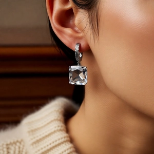 Close-up of model wearing silver C-shaped square glass earrings with a polished finish