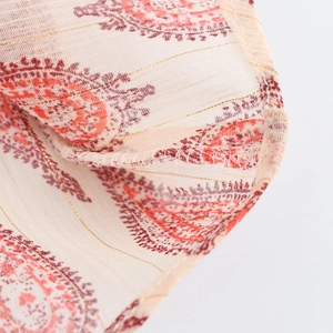 Detailed close-up of ethnic print fabric with gold thread and reinforced overlock stitching