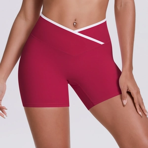 Macro shot of high-waisted red yoga shorts featuring a distinctive white V-cross waistband