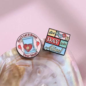 Retro enamel pins featuring colorful quote designs on a decorative seashell display