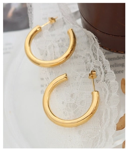 Close-up of golden C-shaped hoop earrings on elegant lace background with a vintage vibe