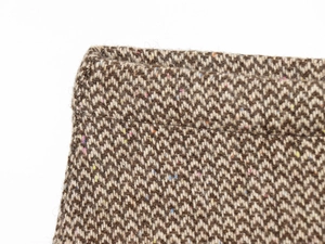 Dettaglio del tessuto in tweed a spina di pesce marrone con accenti di fibre colorate