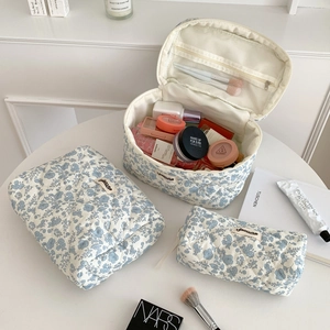 Three-piece set of white and blue floral quilted cotton makeup bags with top handle