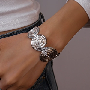 Close-up of silver-tone spiral geometric open bangle with a vintage bohemian metallic style