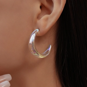 Macro view of C-shaped iridescent acrylic earring with pearlescent finish on model