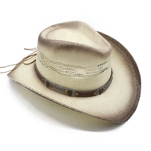Detail of hand-woven straw cowboy hat featuring metal studs and decorative brown leather trim