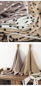 Detail of beige and brown polka dot silk scarf with smooth texture and pearl necklace