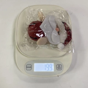 Detailed view of plush Santa bell ornament on an electronic scale weighing 19.9 grams