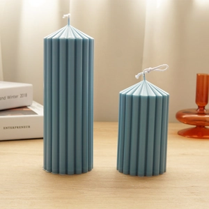 Detailed view of two blue ribbed pillar candles in different heights on a wooden table