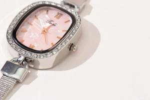 Detail of silver mesh band watch with rhinestone bezel and pink mother of pearl dial