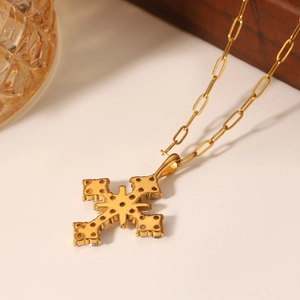 Collier en acier inoxydable doré avec pendentif croix en zircon sur une surface blanche