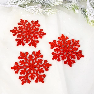 Three glossy red snowflake ornaments set against white fabric with festive pine branches