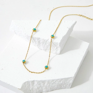 Golden stainless steel necklace featuring blue evil eye charms on white stone blocks