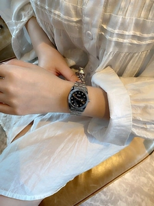 Detail of silver ladies watch with black dial, rhinestone markers and date window