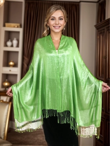 Detail of bright green shimmering shawl with tassels worn by a model in elegant indoor setting