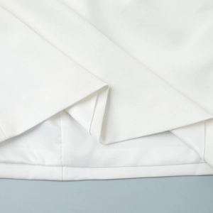 Close-up of white woven fabric hem with neat stitching and smooth matching lining