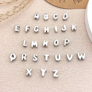Set of 26 silver alphabet beads for DIY jewelry making displayed on a textured background