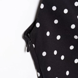 Detail of invisible zipper on black polka dot off-shoulder dress with white spots