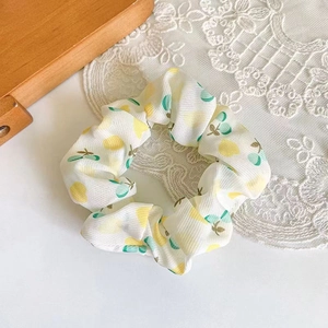 Close-up of white fabric hair scrunchie with yellow lemon pattern on lace and wood