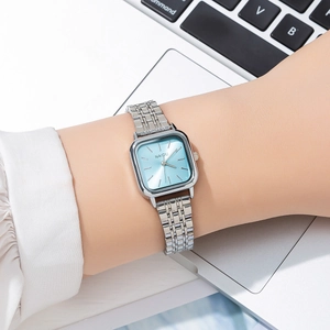 Detail of silver mesh band watch with light blue square dial on a wrist in office