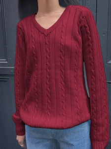 Detailed close-up of V-neck red knitted sweater with classic cable knit texture and long sleeves