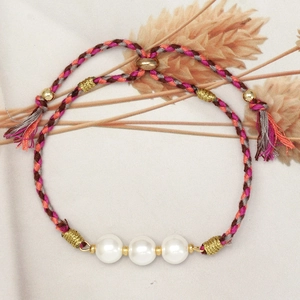Detail of colorful woven cord bracelet with white pearls and gold bead accents