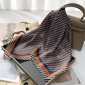Détail d'un foulard en soie aux motifs géométriques bleu et marron sur un plateau élégant