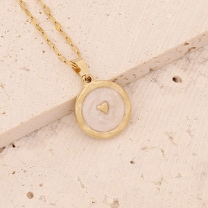 Detailed shot of gold heart owl pendant necklace with cream inlay on stone background