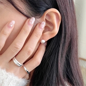 Nahaufnahme eines minimalistischen Silberrings und kleiner Perlenohrstecker am Model