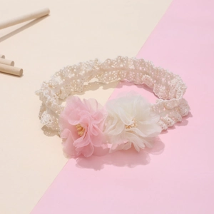 Dettaglio di fiori in chiffon rosa e crema su fascia elastica in pizzo per neonate