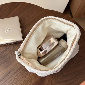 Top view of white knit makeup bag with gold zipper showing spacious interior storage