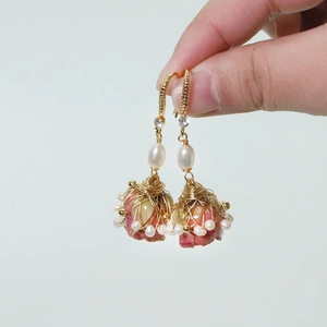 Detail of handmade gold wire-wrapped pink rosebud earrings with white pearls