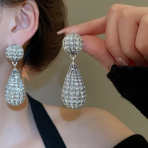 Detail of silver waterdrop earrings with pavé crystals shown worn on ear by model