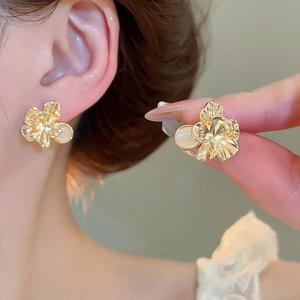 Macro detail of French style cat eye stone flower stud earring with gold plating