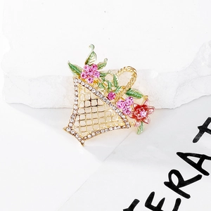 Macro view of floral basket brooch featuring pink rhinestones and green enamel leaf detail