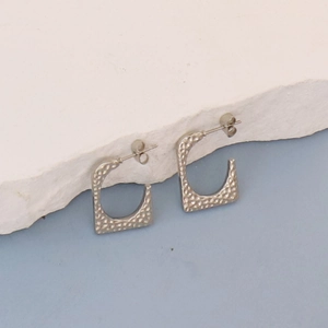 Detailed view of silver square C-shape earrings with unique hammered texture on stone base