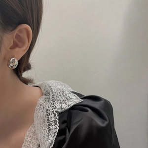 Dettaglio di orecchini a sfera in argento indossati con colletto in pizzo elegante