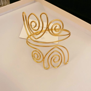 Detalle de brazalete ancho calado con baño de oro y diseño de espiral plisada