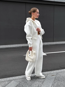 Ensemble survêtement blanc femme avec veste à capuche et pantalon large sur fond gris