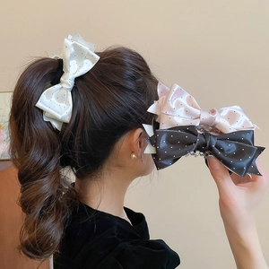 Detail of satin polka dot bow hair clips in cream, pink and black colors for elegant styling