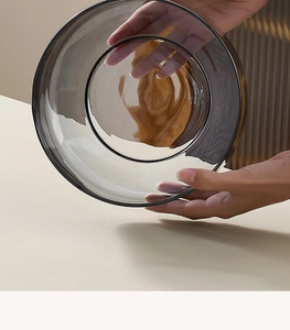 Close-up of hands holding smoky gray glass salad bowl showing texture and transparency
