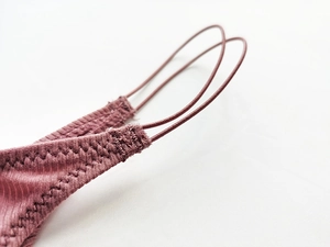 Nahaufnahme der feinen Baumwollrippen und des elastischen Bands am lila Tanga