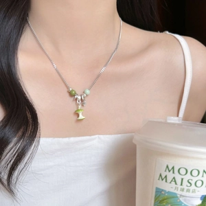 Detail of silver snake chain with green beaded apple core pendant on a female model