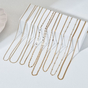 Multiple gold stainless steel necklaces with natural stones on a white geometric stand
